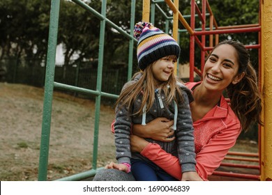 Woman spending time with a girl at the playground. Babysitter playing with a girl at the park.