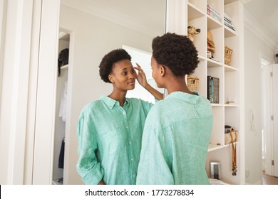  woman spending time at home self isolating and social distancing in quarantine lockdown during coronavirus covid 19 epidemic, taking care of her skin, looking at mirror in her bedroom. - Powered by Shutterstock