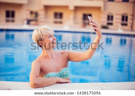 Woman spends time and has relax on the pool with phone. People, summer, holiday and technology concept
