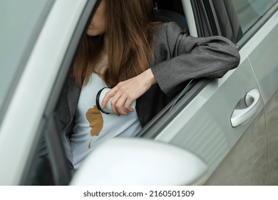 Woman Spilled Coffee On Shirt Behind The Wheel Of A Car. Concept Of Cleaning Stains On Clothes. High Quality Photo