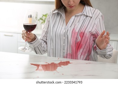 Woman with spilled wine over her shirt and marble table in kitchen, closeup - Shutterstock ID 2233341793