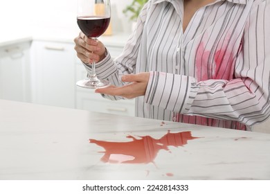 Woman with spilled wine over her shirt and marble table in kitchen, closeup - Shutterstock ID 2242814333