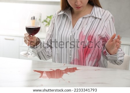 Woman with spilled wine over her shirt and marble table in kitchen, closeup Foto stock © 