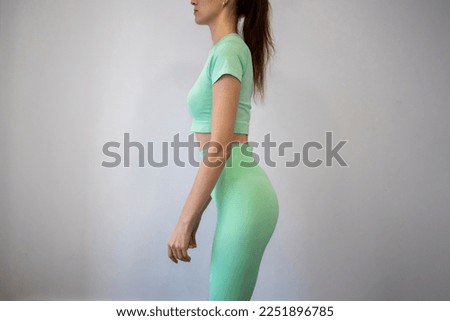 Woman with spinal curvature problem in the lower back hyperlordosis. Anatomy of spinal curvature in hyperlordosis, posture correction. Chiropractic care, back pain relief. Slim girl in a tracksuit
