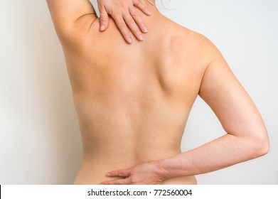 Woman with spine pain is holding her aching back - body pain concept