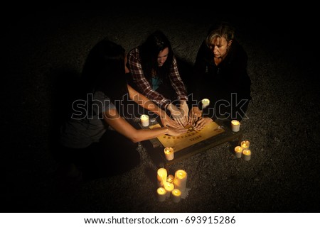 Woman spiritualists communicating with ghosts through spiritual board in summer night