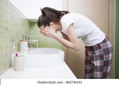 Woman Splashing Face With Water Above Bathroom Sink