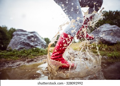 Woman splashing in muddy puddles in the countryside