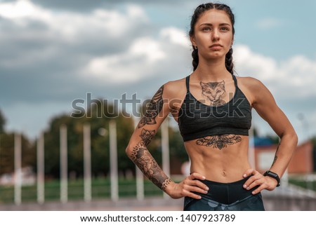 Woman sports coach, summer city, fitness workout. Motivation strength mind thoughts. Tattoo cats on figure. Smart bracelet, watch. Free space. Beautiful girl in morning on run.