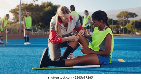 Woman, sports and knee injury in hockey training, practice or game on a blue turf with coach and team. Sport mentor helping female in leg pain, accident or bruise from physical activity during match - Powered by Shutterstock