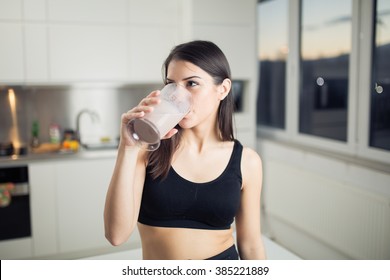 Woman in sportswear  drinking sweet banana chocolate protein powder milkshake smoothie.Drinking protein after workout.Whey,banana and low fat milk sport nutrition diet after gym.Healthy lifestyle