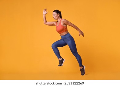 Woman in sportswear running on orange background - Powered by Shutterstock