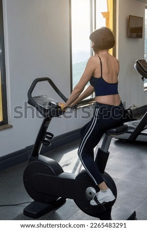 A woman in sportswear simulator pedals looking out the window.