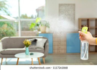 Woman Spraying Air Freshener At Home