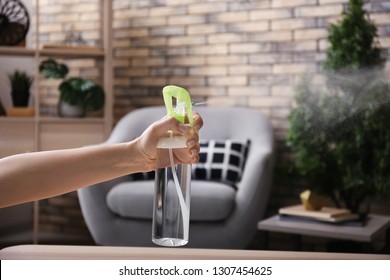 Woman Spraying Air Freshener At Home