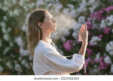Woman spraying facial mist on her face, summertime skincare concept - Shutterstock ID 2321426365