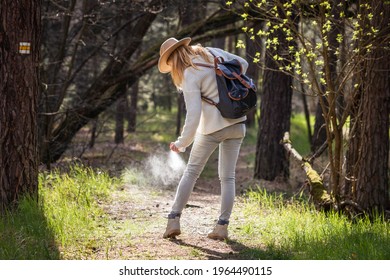 Woman spraying insect repellent against tick at her legs. Protection against mosquito bite during hike in woodland - Shutterstock ID 1964490115