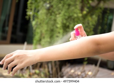 Woman spraying insect repellents on skin in the garden with spray bottle