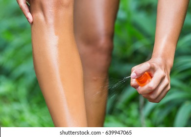 Woman Spraying Mosquito Repellent On Leg Skin. Woman Using Insect Repellent Bug Spray Bottle On Legs, Body And Clothing Outdoor In Nature Forest. Prevention For Zika Virus Affecting Tropical Areas.