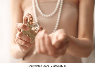 Woman spraying perfume onto wrist indoors, closeup