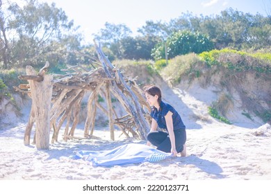 Woman Spreading A Beach Towel On The Beach