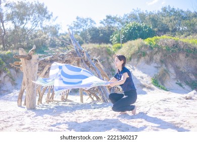 Woman Spreading A Beach Towel On The Beach