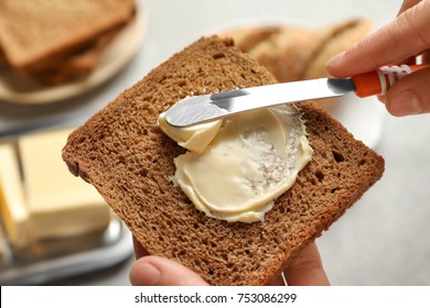 Woman Spreading Butter On Slice Of Bread, Closeup