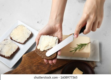 Woman spreading fresh butter onto slice of bread