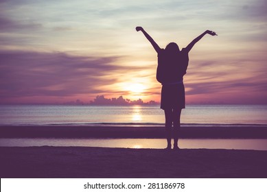 Woman spreading hands with joy and inspiration at sunrise.