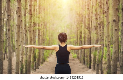 Woman spreading her arms in the forest back view: balance, spirituality and nature concept 