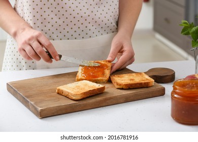 Woman spreading tasty peach jam on bread slice in kitchen - Powered by Shutterstock