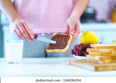 Woman Spreads Nut Chocolate Cream On Toast Bread For A Dessert At Home 