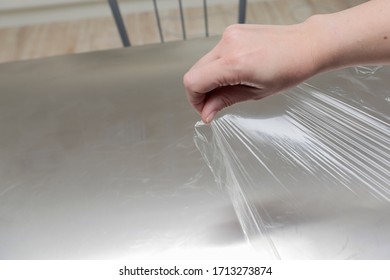 A Woman Spreads Plastic Wrap To Pack Her Food In The Kitchen In Her Home.