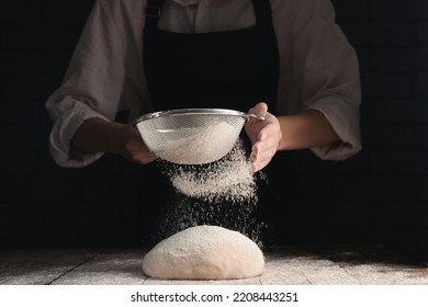 Woman sprinkling flour over dough at wooden table on dark background, closeup - Powered by Shutterstock