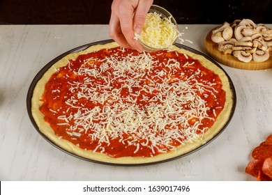 Woman Sprinkling Pizza With Shredded Mozzarella Cheese.