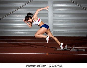 Woman sprinter leaps from starting block.