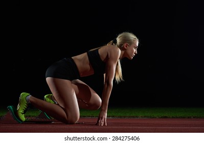 woman  sprinter leaving starting blocks on the athletic  track. Side view. exploding start - Powered by Shutterstock