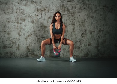 A Woman Squats With A Weight