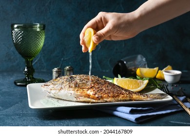 Woman squeezing lemon juice onto fried dorado on plate, closeup - Powered by Shutterstock