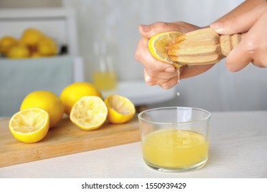 Woman squeezing lemon juice with reamer at white wooden table, closeup. Space for text - Powered by Shutterstock