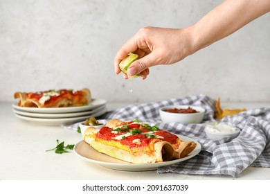 Woman Squeezing Lime Juice Onto Tasty Enchilada On Plate