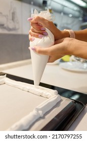 Woman Squeezing Protein Cream From Pastry Bag On Baking Sheet Covered With Parchment Paper. Closeup, Only Hands Visible