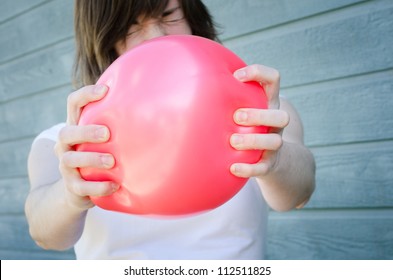 Woman Squeezing Red Balloon In Tension, Ready To Pop