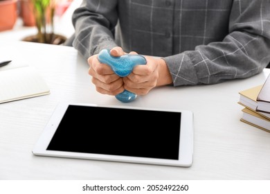 Woman Squeezing Stress Ball While Using Tablet Computer