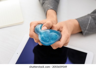 Woman Squeezing Stress Ball While Using Tablet Computer