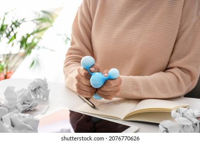 Woman Squeezing Stress Ball While Working In Office