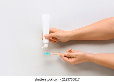 Woman Squeezing Tooth Paste Onto Brush On White Background