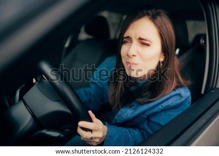 
Woman Squinting and Driving Not Having Proper Visibility. Unhappy frustrated driver having visibility problems due to traffic and meteorological conditions

