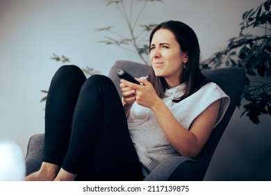 
Woman Squinting While Watching TV Needing Her Eyeglasses To See. Myopic Girl Trying To Read Small Captions From A Movie 
