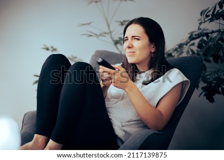 
Woman Squinting while Watching TV Needing Her Eyeglasses to See. Myopic girl trying to read small captions from a movie 
